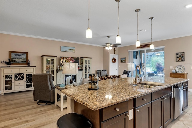 kitchen featuring light stone countertops, dishwasher, sink, an island with sink, and dark brown cabinets