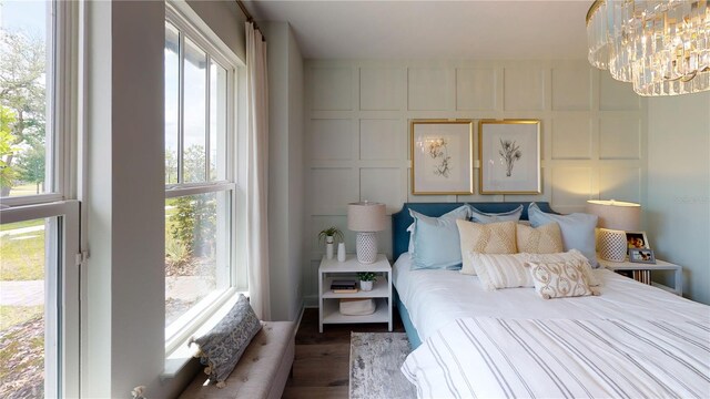 bedroom featuring hardwood / wood-style flooring, multiple windows, and a chandelier