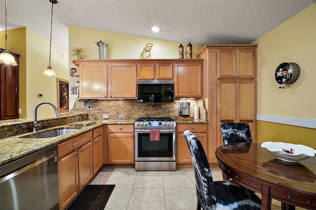 kitchen featuring decorative light fixtures, vaulted ceiling, sink, stainless steel appliances, and light tile patterned floors