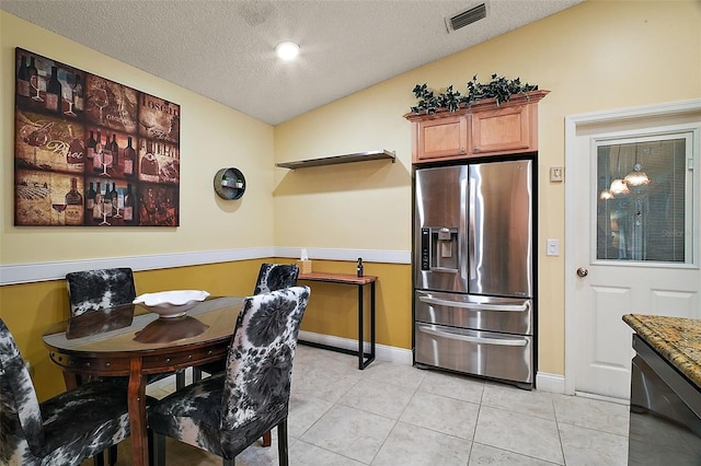 tiled dining room with a textured ceiling and lofted ceiling