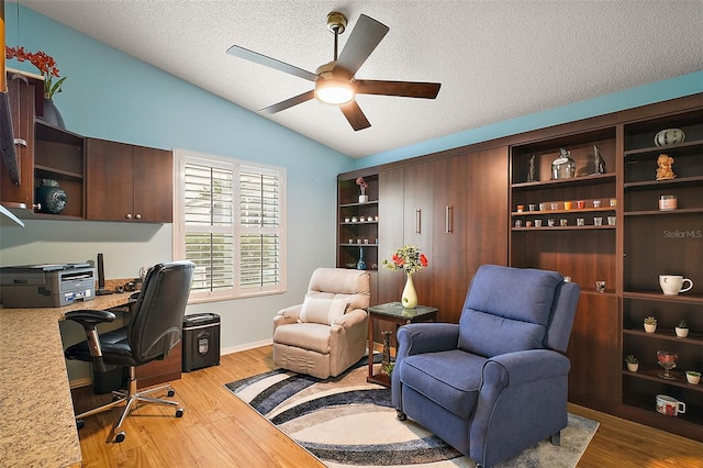 home office featuring ceiling fan, a textured ceiling, lofted ceiling, and light wood-type flooring