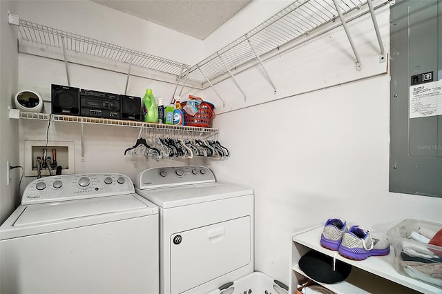 washroom with a textured ceiling, washer and dryer, and electric panel