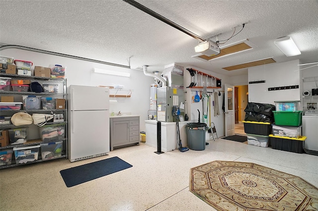 garage featuring washer / dryer, white fridge, a garage door opener, sink, and heating unit