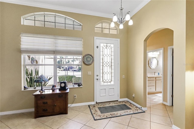 tiled entryway featuring sink, a chandelier, and ornamental molding