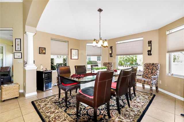 tiled dining area featuring a chandelier, decorative columns, and beverage cooler