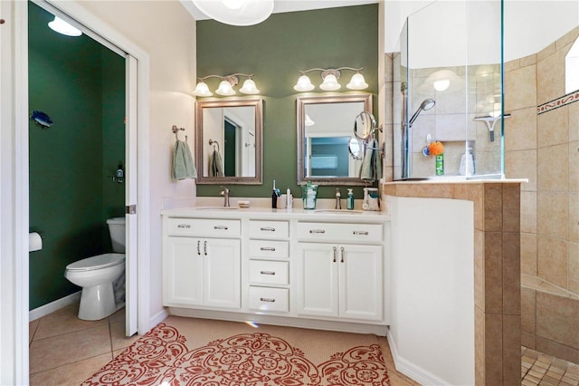 bathroom featuring tile patterned floors, vanity, a tile shower, and toilet