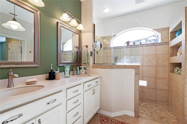 bathroom with tile patterned flooring, vanity, and a tile shower