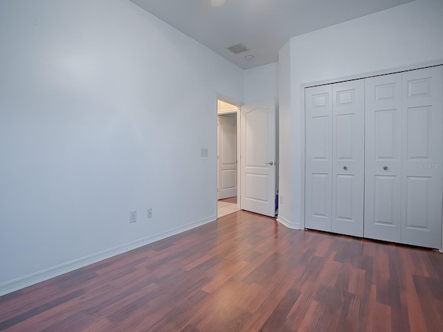 unfurnished bedroom featuring a closet and dark wood-type flooring