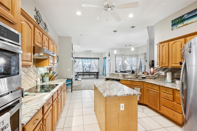 kitchen featuring ceiling fan, light stone countertops, backsplash, a kitchen island, and appliances with stainless steel finishes