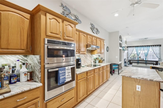 kitchen featuring stainless steel double oven, light tile patterned floors, decorative backsplash, black electric stovetop, and a kitchen island