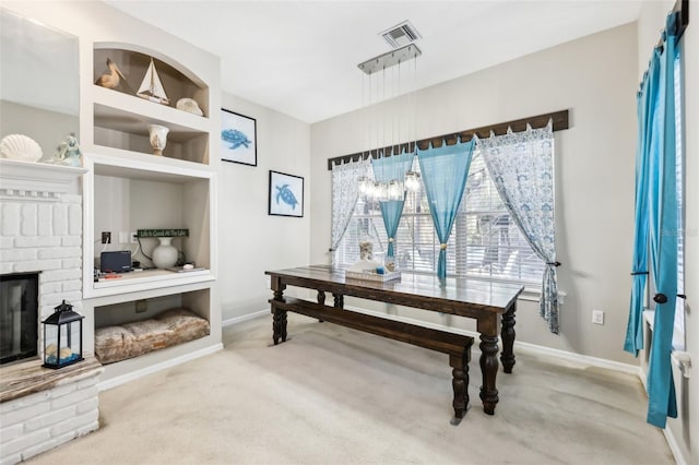 office area with built in features, carpet floors, and a brick fireplace