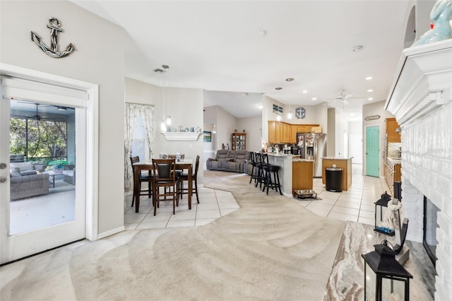 dining room with ceiling fan, a fireplace, lofted ceiling, and light carpet