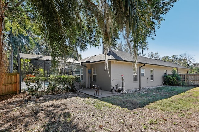 back of property featuring a lawn, a lanai, and a patio