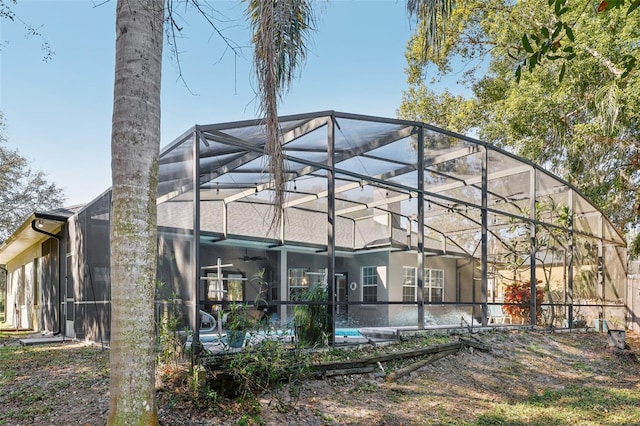 rear view of property with glass enclosure and ceiling fan