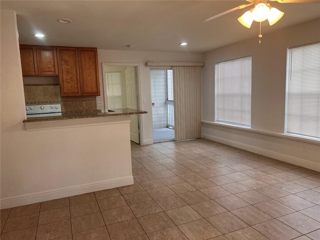 kitchen featuring ceiling fan, tasteful backsplash, light tile patterned flooring, stone counters, and range