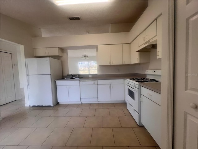 kitchen with white appliances, hanging light fixtures, light tile patterned floors, white cabinets, and sink