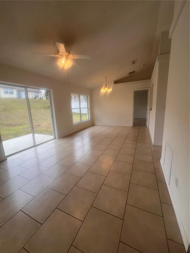 unfurnished room with ceiling fan with notable chandelier, vaulted ceiling, and light tile patterned floors