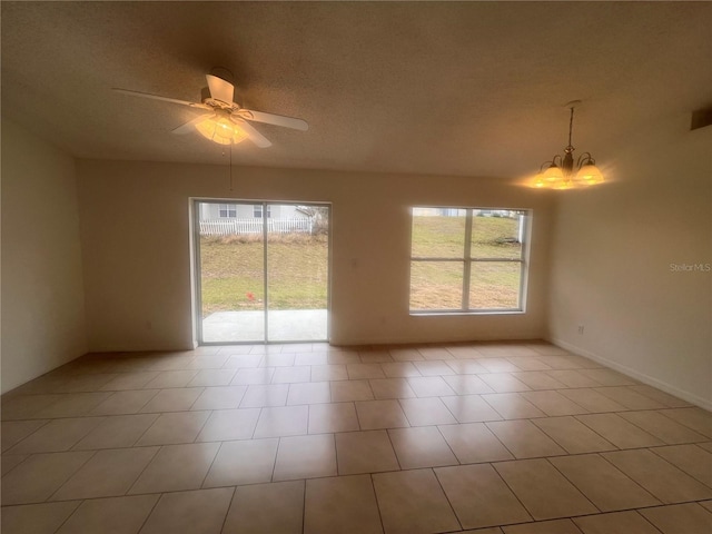 spare room featuring a textured ceiling, light tile patterned flooring, and ceiling fan with notable chandelier