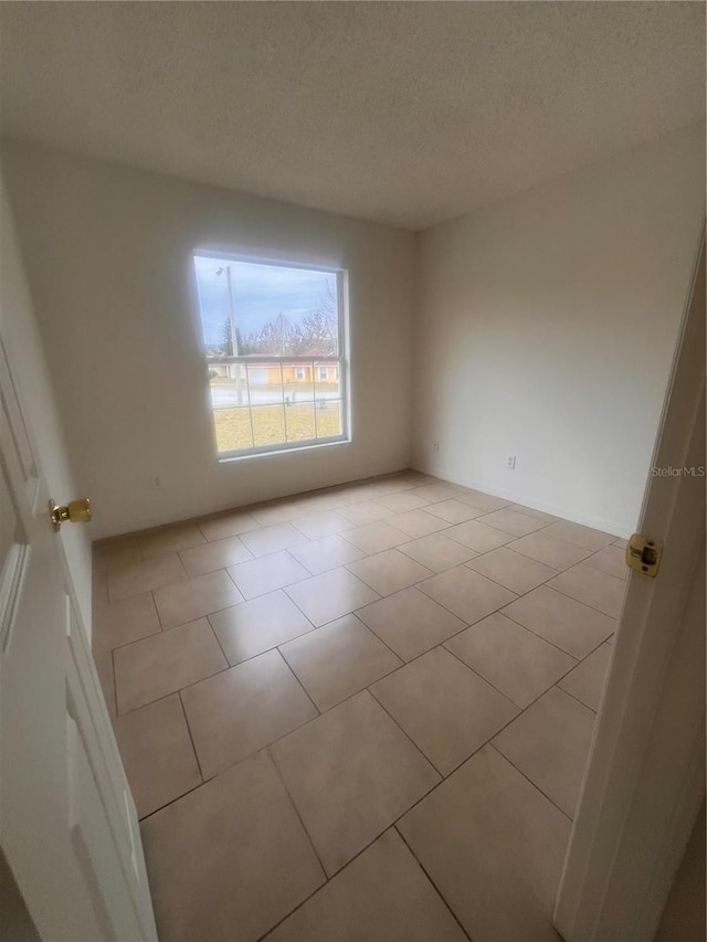 unfurnished room featuring a textured ceiling and light tile patterned flooring