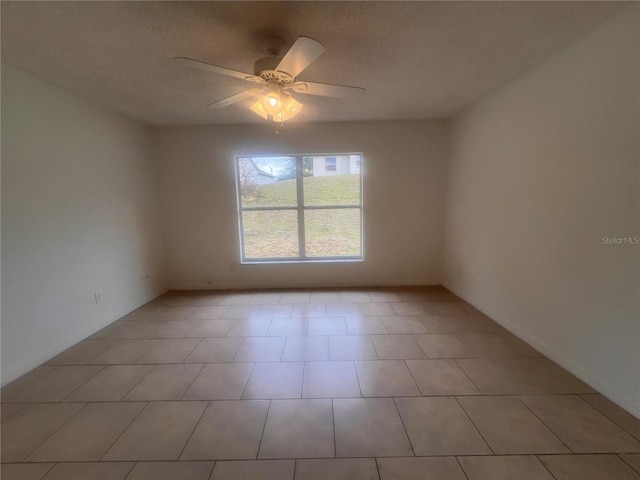 empty room with a textured ceiling, ceiling fan, and light tile patterned floors