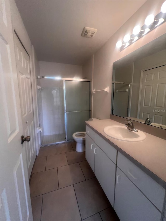 bathroom with a shower with door, tile patterned flooring, vanity, and toilet