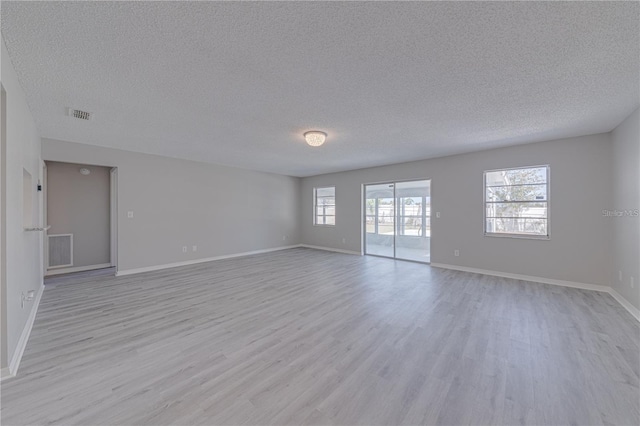 spare room featuring a textured ceiling and light hardwood / wood-style floors