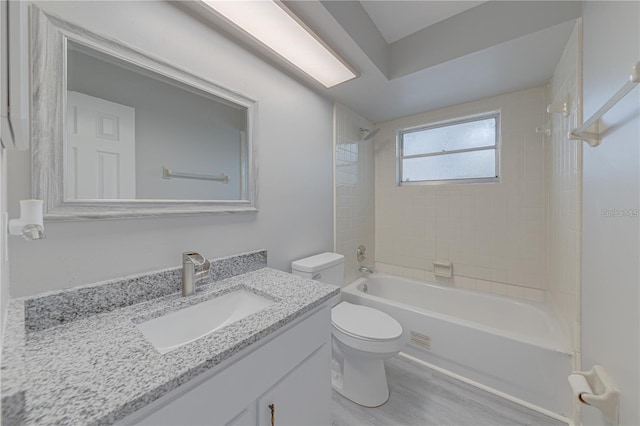 full bathroom featuring vanity, wood-type flooring, tiled shower / bath combo, and toilet