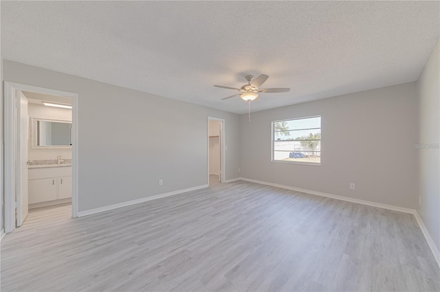 empty room featuring ceiling fan, light hardwood / wood-style flooring, and a textured ceiling