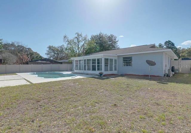 back of property with a sunroom, a fenced in pool, and a yard