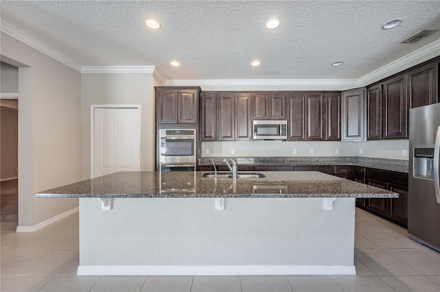 kitchen with a kitchen bar, stainless steel appliances, and a kitchen island with sink