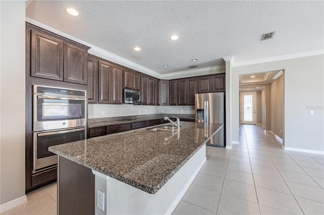 kitchen with dark brown cabinetry, stainless steel appliances, a kitchen island with sink, and sink