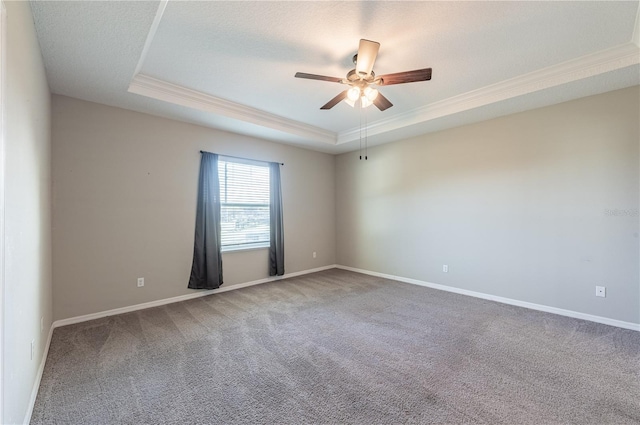 empty room featuring carpet, ceiling fan, ornamental molding, a textured ceiling, and a tray ceiling