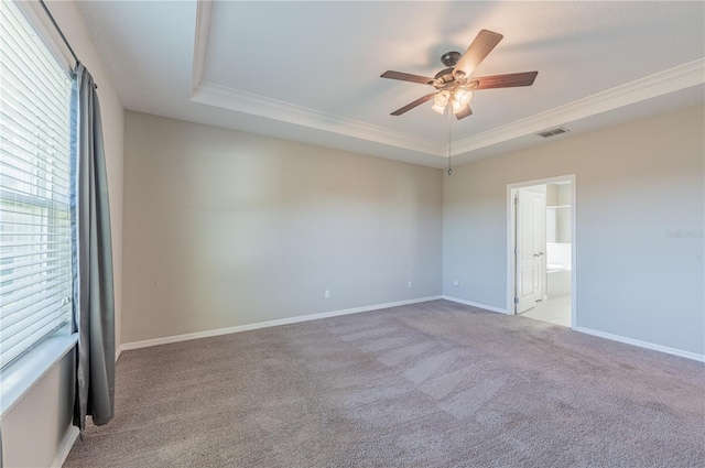 carpeted spare room with a tray ceiling and ceiling fan