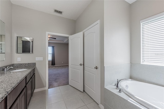 bathroom featuring a textured ceiling, vanity, ceiling fan, a relaxing tiled tub, and tile patterned flooring