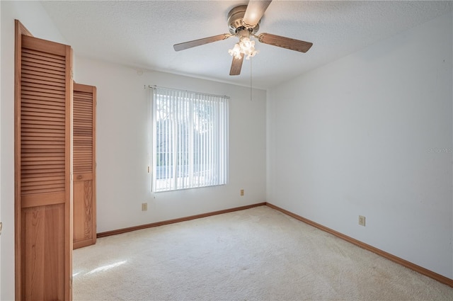 unfurnished bedroom featuring ceiling fan, light colored carpet, a textured ceiling, and a closet