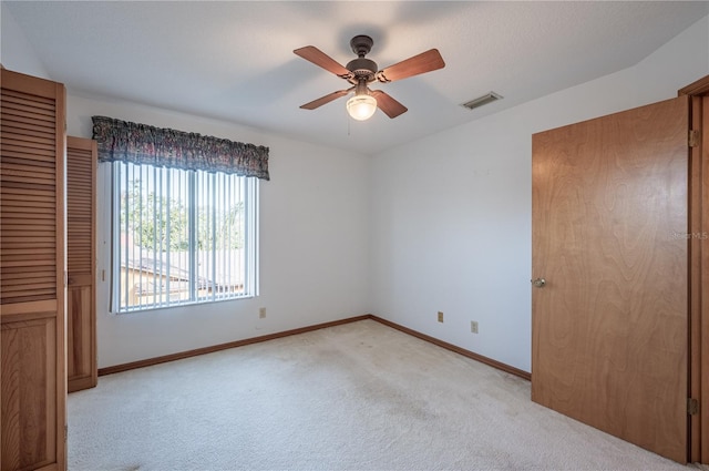 carpeted spare room featuring ceiling fan