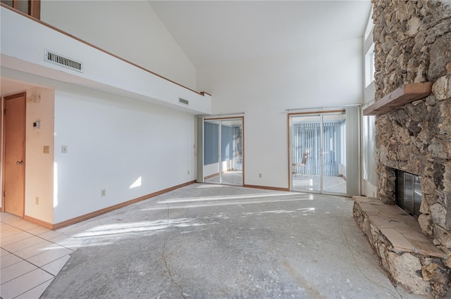 unfurnished living room featuring a high ceiling, a stone fireplace, and a wealth of natural light