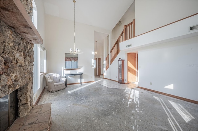 unfurnished living room featuring a fireplace, a high ceiling, and an inviting chandelier