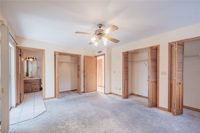 unfurnished bedroom with connected bathroom, ceiling fan, and two closets