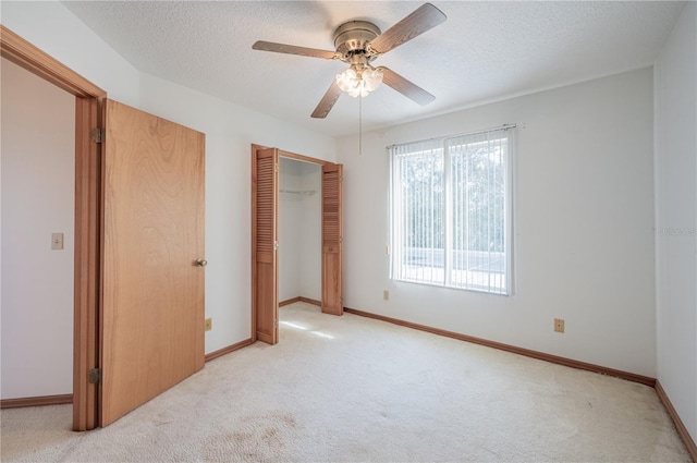 unfurnished bedroom with ceiling fan, a closet, light carpet, and a textured ceiling