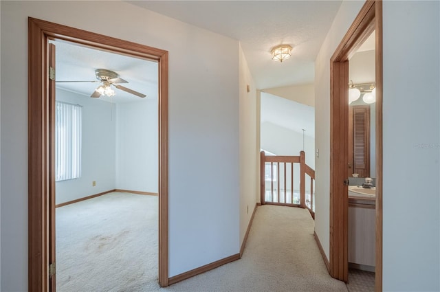 hallway featuring a textured ceiling, light colored carpet, and sink