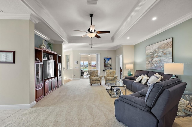 living room with light carpet, a tray ceiling, ceiling fan, and ornamental molding