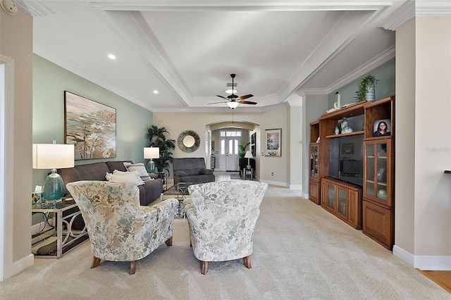 carpeted living room with ceiling fan, crown molding, and a tray ceiling