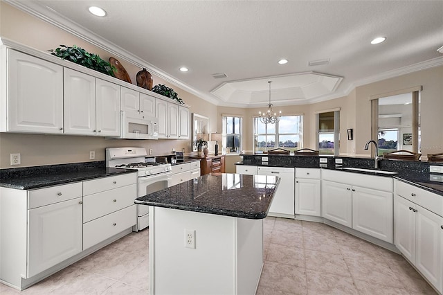 kitchen featuring sink, a kitchen island, a raised ceiling, white appliances, and white cabinets