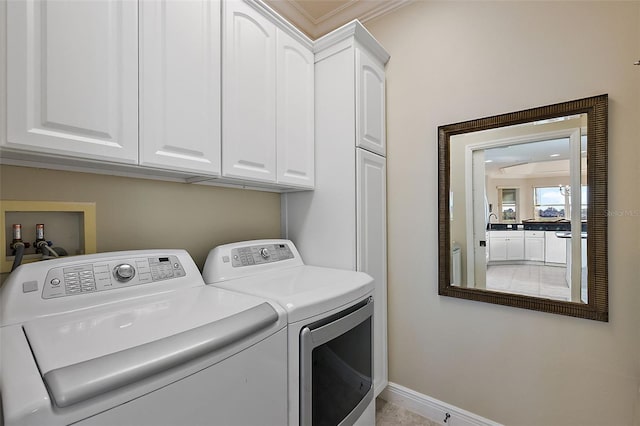 laundry area featuring washing machine and clothes dryer, cabinets, and ornamental molding