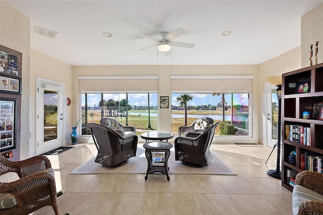 interior space with a water view, ceiling fan, and a healthy amount of sunlight