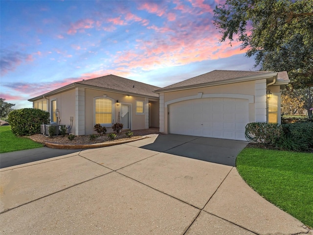 ranch-style house featuring cooling unit, a garage, and a lawn