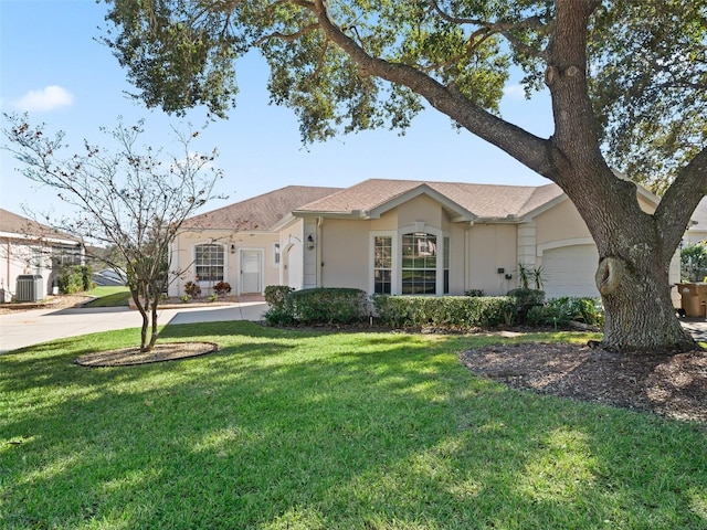 ranch-style home featuring cooling unit, a garage, and a front yard