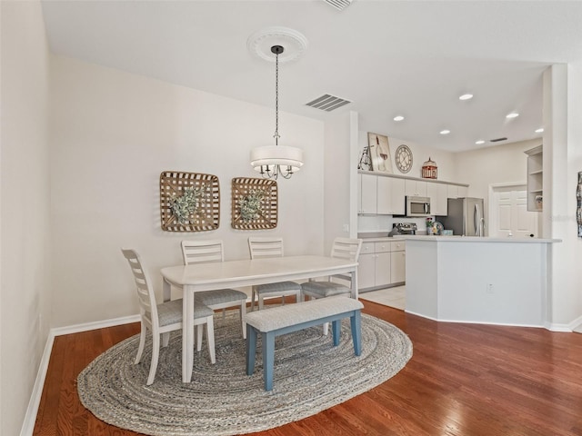 dining area with hardwood / wood-style floors and a notable chandelier