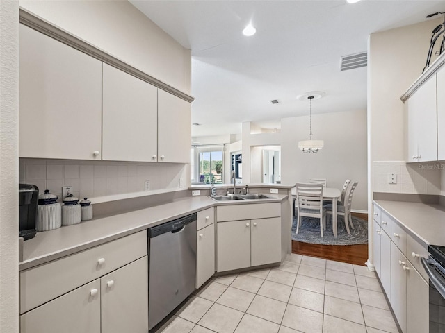 kitchen featuring sink, hanging light fixtures, appliances with stainless steel finishes, white cabinets, and backsplash